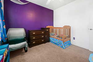 Carpeted bedroom with ceiling fan and vaulted ceiling