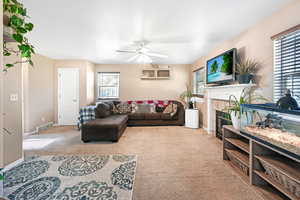 Living area featuring light colored carpet, a tile fireplace, and a ceiling fan
