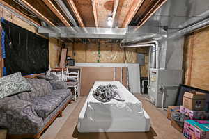 Unfinished basement featuring heating unit, electric panel, and carpet flooring