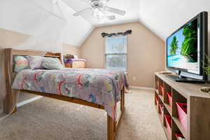 Bedroom with light carpet, vaulted ceiling, a ceiling fan, and a textured ceiling