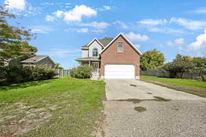 Traditional-style house featuring driveway, brick siding, covered porch, and a garage