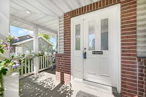 Property entrance featuring a porch and brick siding