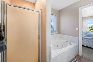 Bathroom with connected bathroom, a jetted tub, tile patterned flooring, a shower stall, and carpet