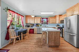 Kitchen featuring appliances with stainless steel finishes, light countertops, light wood-style floors, a center island, and a textured ceiling
