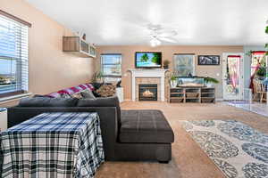 Living room featuring healthy amount of natural light, a tile fireplace, carpet, and ceiling fan