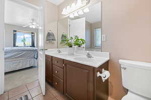 Ensuite bathroom with light tile patterned flooring, double vanity, light carpet, and a ceiling fan