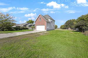 View of side of home featuring concrete driveway, a garage, and brick siding