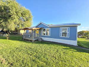Manufactured / mobile home featuring a front lawn, a metal roof, and a wooden deck