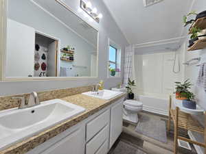 Bathroom with shower / bath combo, double vanity, and dark wood-type flooring