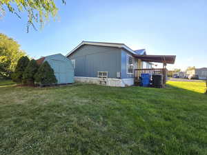 Back of house featuring a yard and a storage unit