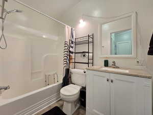 Full bathroom featuring shower / bathtub combination with curtain, vanity, and dark wood-style flooring