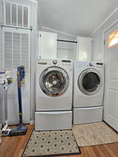 Laundry room featuring light wood finished floors, a heating unit, a textured ceiling, washer and clothes dryer, and cabinet space