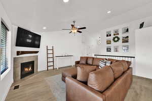 Living room featuring vaulted ceiling, light wood-type flooring, a chandelier, a tile fireplace, and recessed lighting