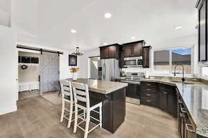 Kitchen featuring stainless steel appliances, a breakfast bar, a center island, light wood finished floors, and dark brown cabinetry