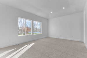 Empty room with light colored carpet and recessed lighting