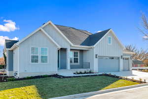 View of front of house featuring board and batten siding, a front yard, roof with shingles, and concrete driveway