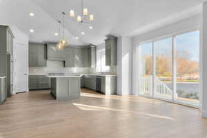 Kitchen with gray cabinets, lofted ceiling, a kitchen island, decorative light fixtures, and light wood-style floors