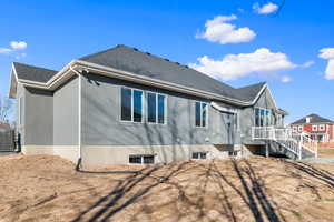 Back of house with a shingled roof and stairs