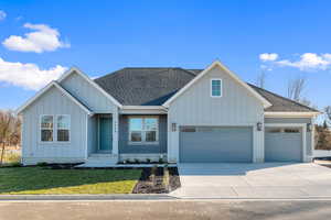 Modern inspired farmhouse with board and batten siding, a shingled roof, driveway, and a front yard
