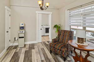 Living area featuring wood finished floors, a chandelier, vaulted ceiling, and washing machine and clothes dryer