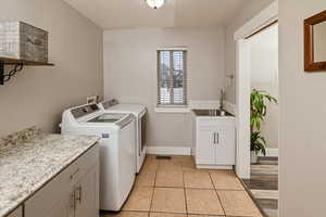 Washroom featuring light tile patterned flooring, washing machine and dryer, and cabinet space