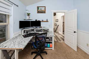Office space featuring wainscoting, vaulted ceiling, and light carpet