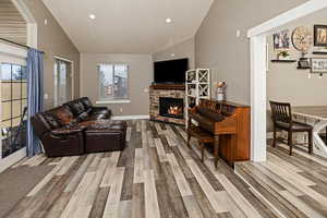 Living area with vaulted ceiling, a fireplace, recessed lighting, and light wood-style floors