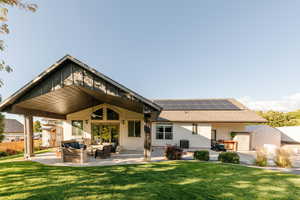 Rear view of property featuring outdoor lounge area, a patio area, solar panels, and stucco siding