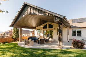 Rear view of house featuring an outdoor hangout area, a patio, ceiling fan, roof with shingles, and roof mounted solar panels