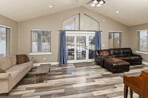 Living room with healthy amount of natural light, light wood-style floors, recessed lighting, high vaulted ceiling, and ceiling fan