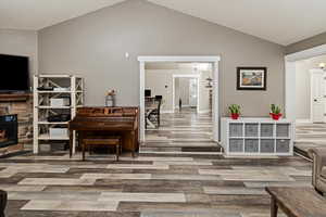 Sitting room with lofted ceiling, a fireplace, and light wood-style flooring