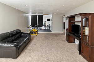Living area with a textured ceiling, light colored carpet, and recessed lighting