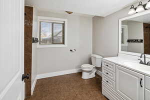 Full bath with a textured ceiling, vanity, dark tile patterned floors, and a shower