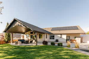 Rear view of house featuring outdoor lounge area, a shingled roof, a patio, roof mounted solar panels, and stucco siding