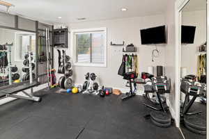 Exercise room with rubber floors, a textured ceiling, and recessed lighting