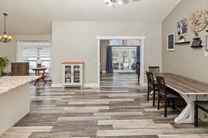 Dining room with a chandelier, light wood-style flooring, and lofted ceiling