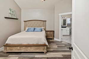 Bedroom with connected bathroom and dark wood-style flooring