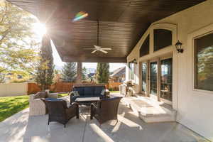 Fenced backyard featuring an outdoor hangout area, a ceiling fan, and a patio