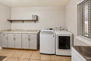 Laundry room with light tile patterned floors, independent washer and dryer, and cabinet space