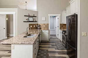 Kitchen featuring a peninsula, light stone counters, stainless steel appliances, open shelves, and tasteful backsplash