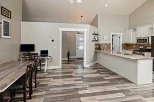 Kitchen with a peninsula, light stone countertops, white cabinets, tasteful backsplash, and stainless steel appliances