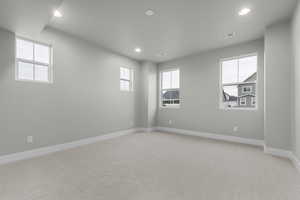 Unfurnished room with light colored carpet, recessed lighting, and healthy amount of natural light
