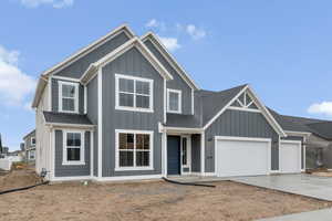 View of front of house with board and batten siding, concrete driveway, an attached garage, and a shingled roof