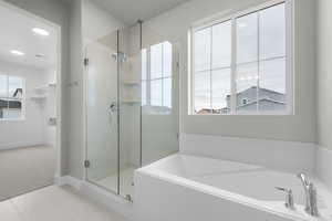 Bathroom featuring a garden tub, a stall shower, light tile patterned floors, and light carpet