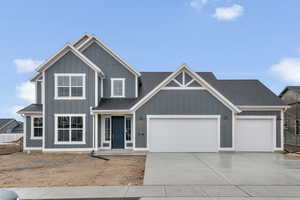 View of front of house with a shingled roof, driveway, an attached garage, and board and batten siding