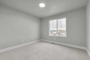 Carpeted spare room featuring baseboards