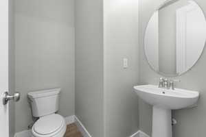 Half bath featuring baseboards and wood finished floors
