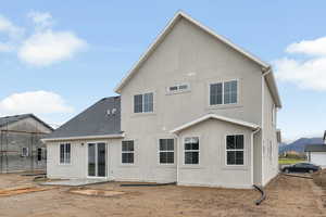 Rear view of property with stucco siding, a patio, and roof with shingles