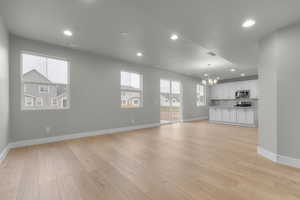 Unfurnished living room with recessed lighting, a chandelier, and light wood-style floors