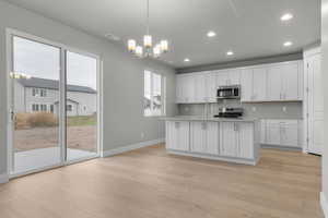 Kitchen with pendant lighting, a kitchen island with sink, white cabinetry, decorative backsplash, and recessed lighting